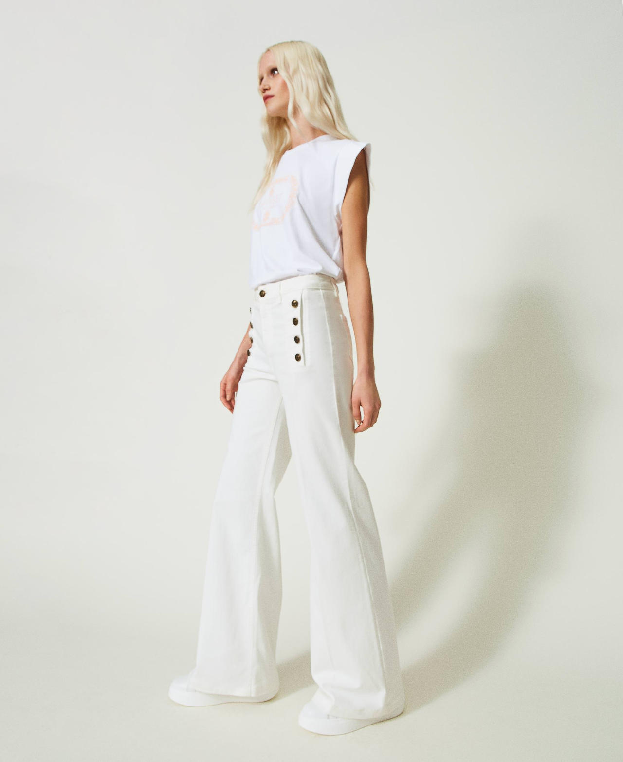 Flared white jeans with decorative buttons