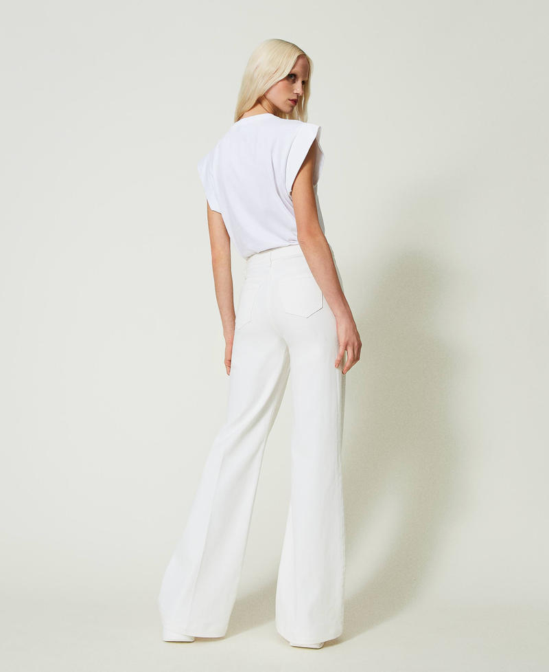 Flared white jeans with decorative buttons