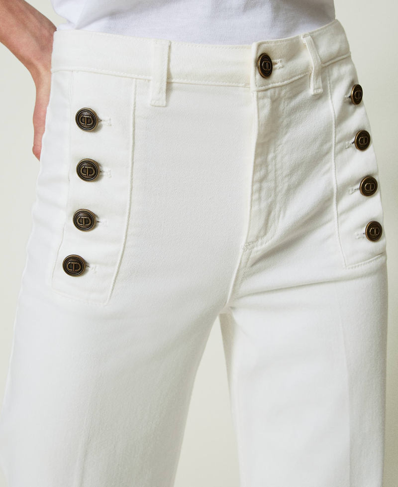Flared white jeans with decorative buttons