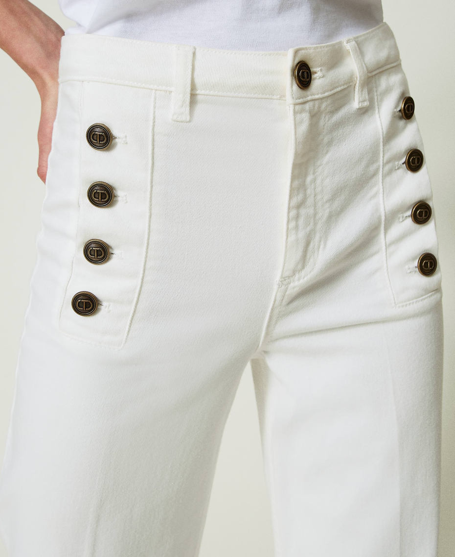 Flared white jeans with decorative buttons